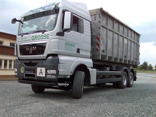 Silberner MAN TGX als Abroller mit Container